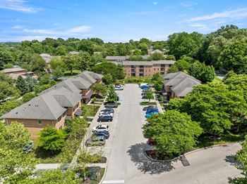 A parking lot is surrounded by trees and a building.